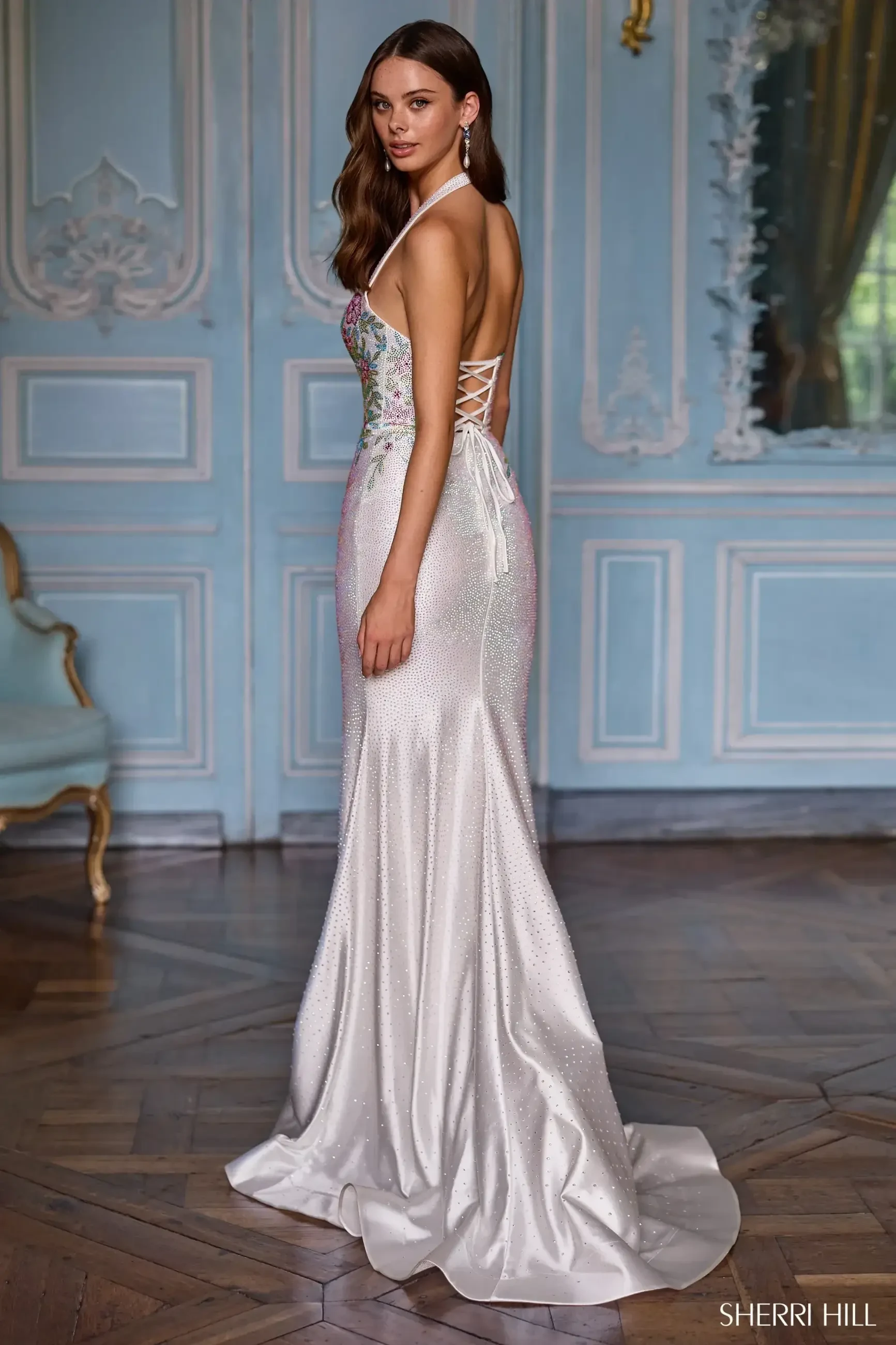 model is wearing an open back silver prom dress