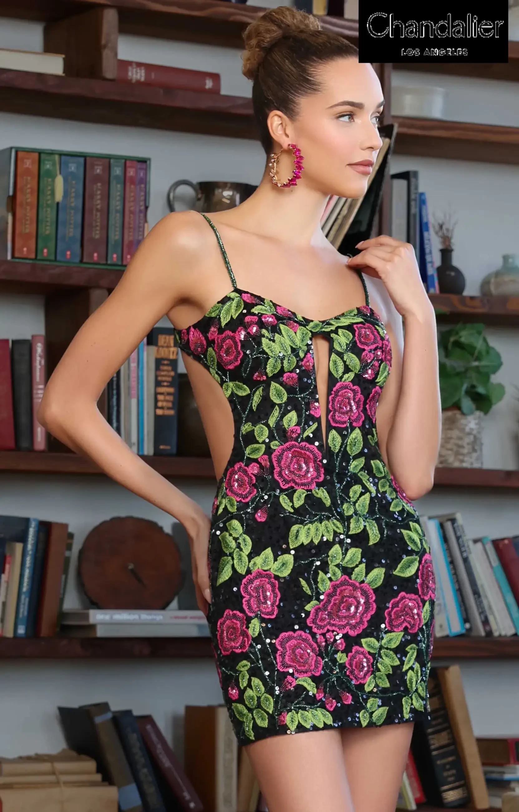 Model is wearing a sequined mini dress with berry and black floral patterns and an open back.