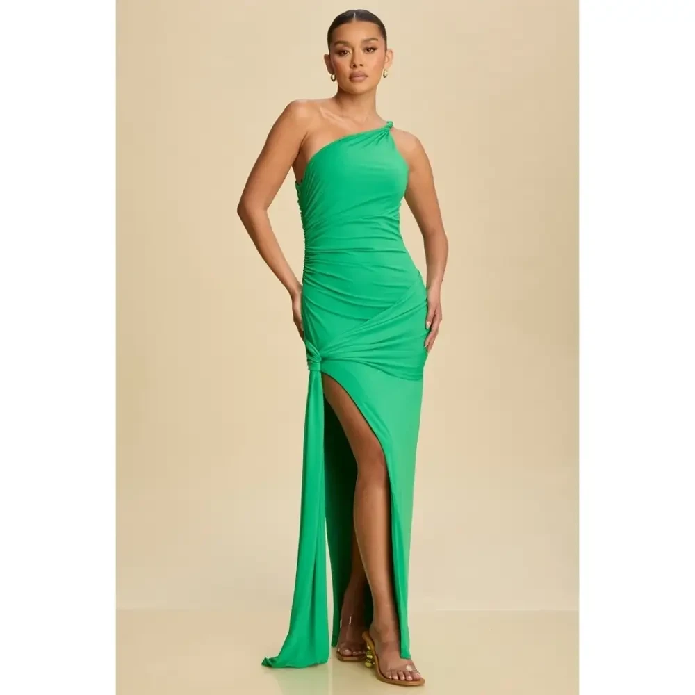 A model wearing a one-shoulder green dress with ruching and a high split.