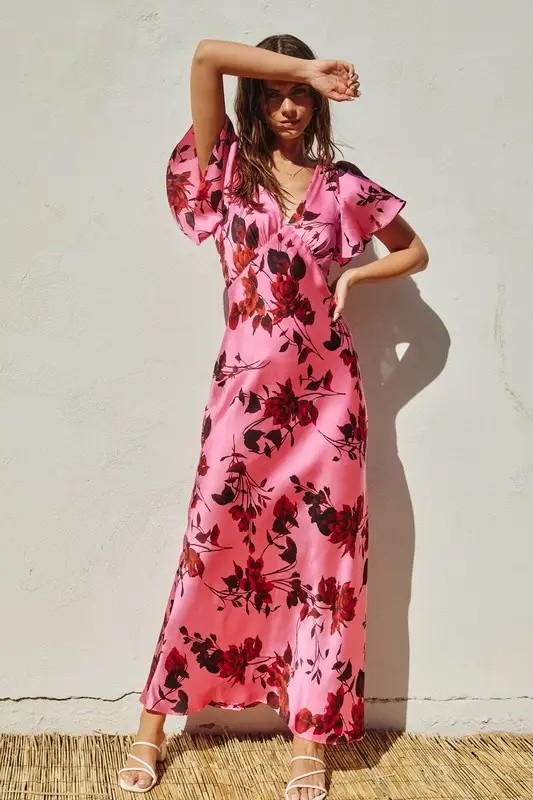 Model is wearing a rose pink floral dress with flutter sleeves 