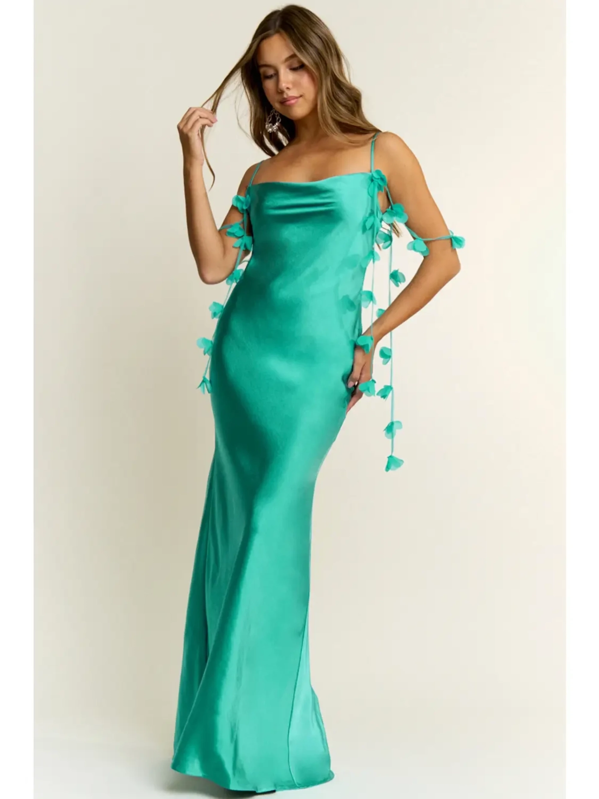 A woman wearing a Jade green long dress with floral accents hanging on the sides, standing against a neutral background.
