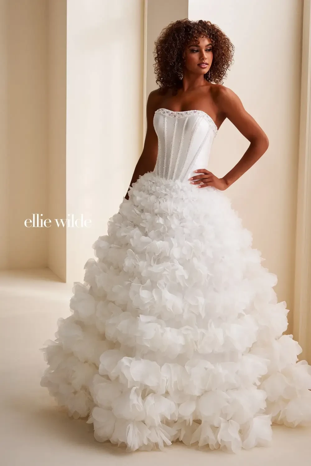 A woman wearing a strapless white wedding dress with a ruffled skirt.